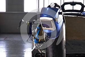 Welding equipment in a car repair station, helmet hanging on a gas tank, no people