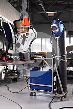 Welding equipment in a car repair station, helmet hanging on a gas tank, no people