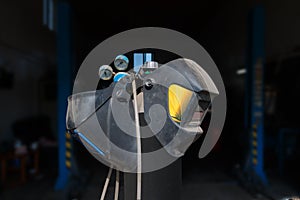 Welding equipment, helmet hanging on a gas cylinder, two welder masks. forgotten dusty equipment