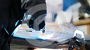 Welding industrial: worker repair detail in car service, close up