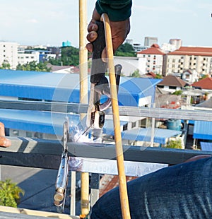 Welding of metal structures with soldering steel beam structure on extension of a building on construction site. Sparks and smoke