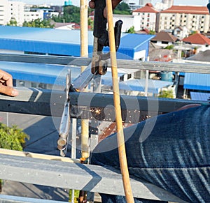 Welding of metal structures with soldering steel beam structure on extension of a building on construction site. Sparks and smoke