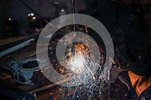 Welding old metal car part at workshop, sparks and smoke flying around, closeup detail