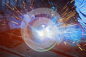 During welding, sparks are produced as argon gas is used to steel that smoke in a factory