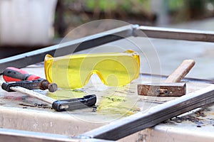 Welding work. Metal profile, safe glasses, hammer and clamp on a metal table. Tools for electro welding. Hand tools