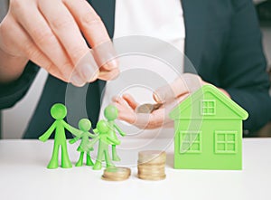 Welfare benefits koncept. Hands of woman making a gesture of protection over family and home with piggy bank. House construction