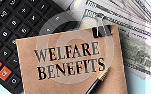 WELFARE BENEFITS - words on brown paper on the background of calculator and banknotes