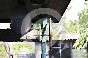 A well with a bucket in a European village. Sunny day. Metal bucket for a water well. Detail of a well with a tin bucket in the