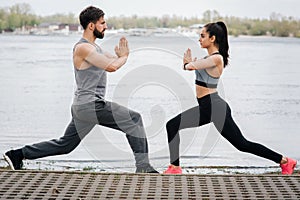 Well-built and gorgeous people are posing at the adge of the river on the bridge. They are squating and kepping their photo