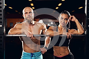 Well-built man and his strong girlfriend posing at the gym