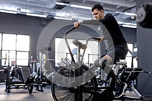 well-built slim sportsman in stylish sportswear working out at gym