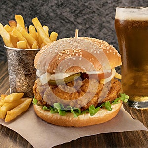 a well crafted southern fried chicken burger served with a side of fries and a bottle of beer