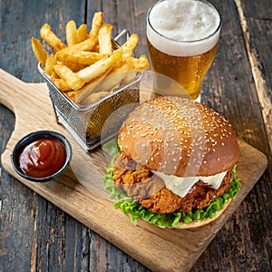 a well crafted southern fried chicken burger served with a side of fries and a bottle of beer
