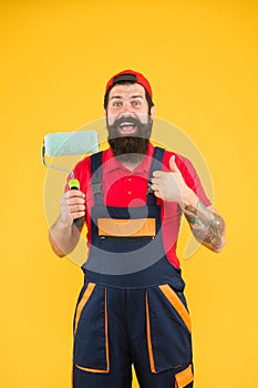 Well done. repair success. bearded man worker with roller tool. hipster builder in cap yellow background. erector photo