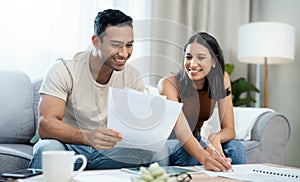 Well done on saving this month, babe. a young couple sitting together in their living room at home and calculating their