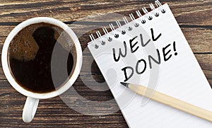 WELL DONE text on notebook with coffee on wooden background