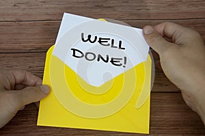 Well done text on white notepad with hand opening the envelope. Motivational concept