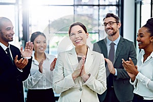 Well done, you deserve this. a succesful businesswoman being applauded by her colleagues in the office.