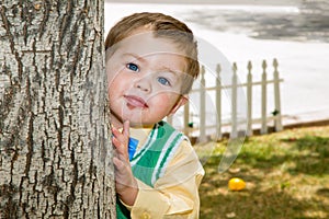 Well Dressed Boy Peeks Around A Tree