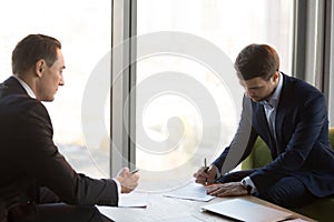 Well-dressed businessmen signing contract during business meetin