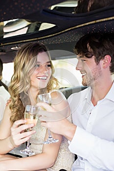 Well dressed couple drinking champagne in a limousine