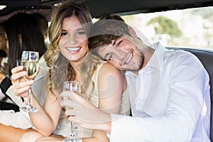 Well dressed couple drinking champagne in a limousine