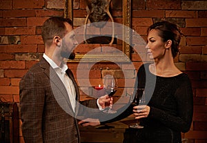 Well-dressed couple with glass of red wine in cozy home interior