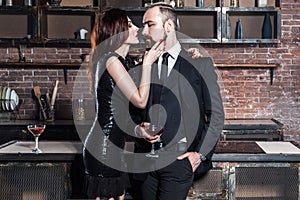 Well dressed famous couple in loft interior. Couple holding gla