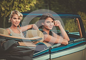 Well-dressed ladies in a classic convertible