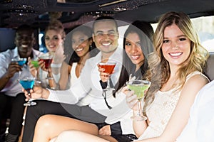 Well dressed people drinking cocktails in a limousine