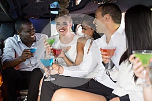 Well dressed people drinking cocktails in a limousine