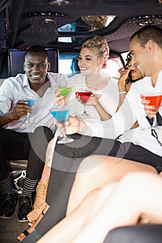Well dressed people drinking cocktails in a limousine