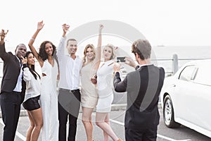 Well dressed people taking pictures next to a limousine