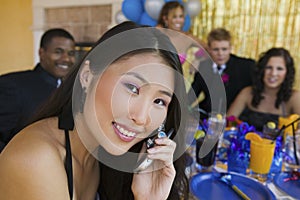 Well-dressed teenager girl using cell phone at school dance