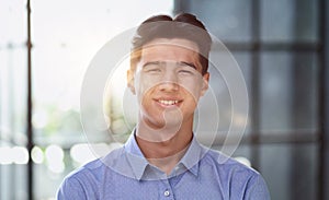 Well dressed young Asian businessman smiling confidently while standing alone in a bright modern office