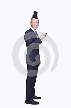 Well-dressed young man with Mohawk using mobile phone