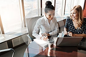 Well get through this quicker if we work together. two businesswomen working together on a laptop in an office.