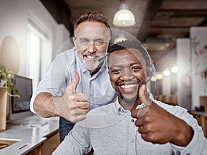 Well get it resolved right on time. two men using headsets and showing thumbs up in a modern office.
