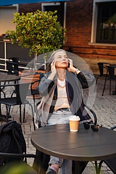 Well-groomed gray-haired woman of 60 years old at  cafe table with coffee