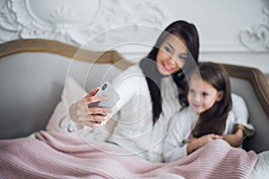 Well-groomed hand of a woman holding a phone taking a selfie with her daughter, little girl