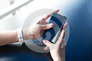 Well-groomed hands of the girl with pink manicure hold the smartphone. A girl using a smartphone