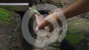 Well-groomed hands of young girl are filled with pure water from natural spring