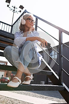 a well-groomed middle-aged woman with a bob haircut listens to music on a walk