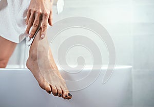Well groomed woman`s feet on bathtub edge