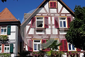 well-kept half-timbered house with red shutters under a steel blue sky