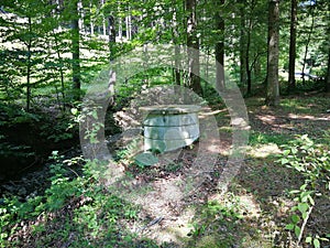 A well made of concrete rings built in the forest next to a stream