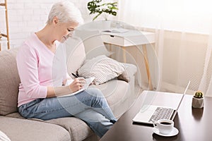 Well organized senior lady writing to-do-list at home