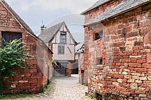 Well-preserved medieval buildings made of red sandstone with tiled roofs and chimneys. Collonges-la-Rouge