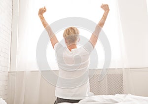 Well slept woman stretching her body in bedroom