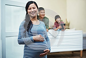 Well soon be a family of four. Portrait of a pregnant woman relaxing with her family at home.